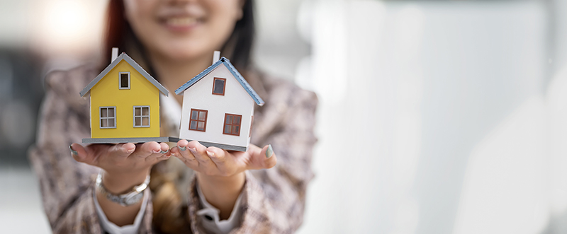 Real estate agent, woman hand holding small house model with copy space.